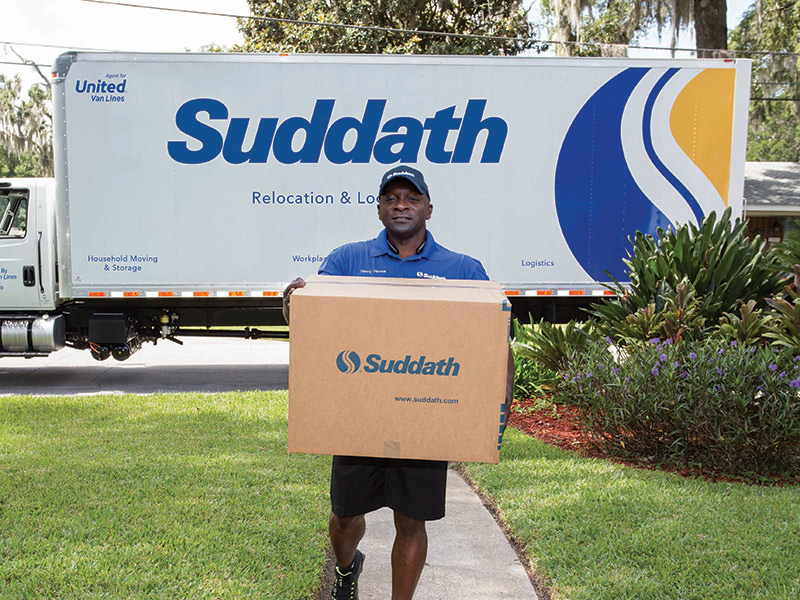 suddath mover carrying moving box in front of suddath truck
