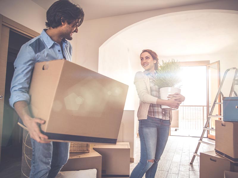smiling couple carrying moving boxes
