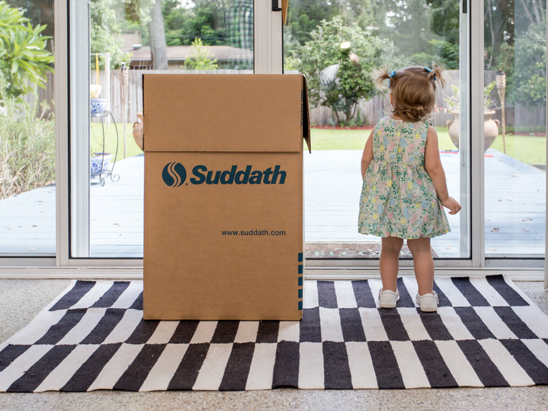 little girl standing next to moving boxes looking out window