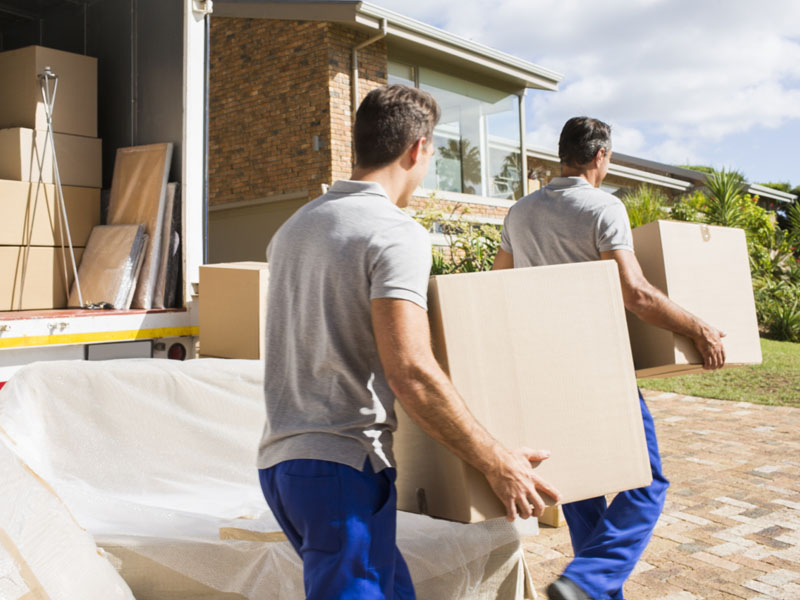 movers carrying boxes from truck into house
