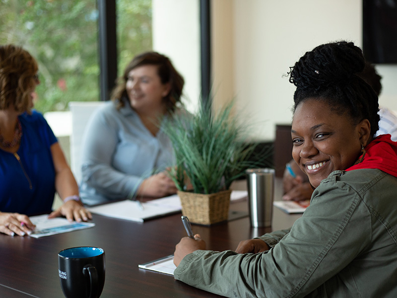 woman writing on paper at conference table