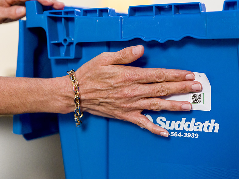 woman placing tracking tag on moving crate